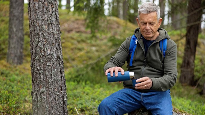 Man dricker kaffe i skogen