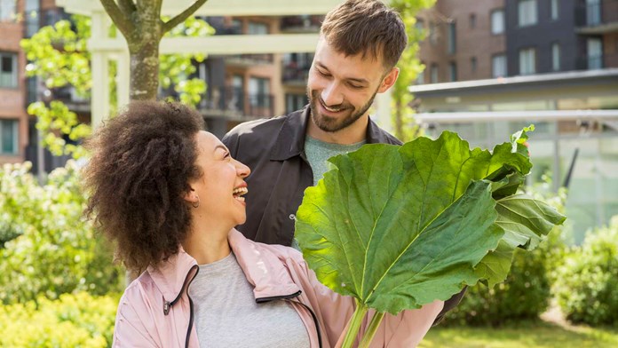 Kvinna på innergård håller i rabarberblad